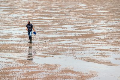 Rear view of man walking on beach