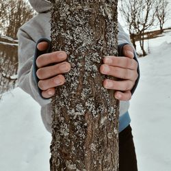 Midsection of man holding tree trunk during winter
