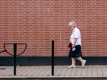 Full length of a boy standing against brick wall