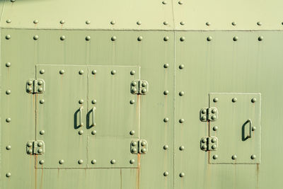 Rusty green metal surface with rivets and secured panels in bright sunlight