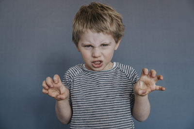 Portrait of boy standing against gray background