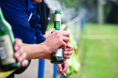 Midsection of man holding beer bottle