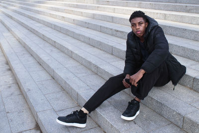 Portrait of young man standing on footpath