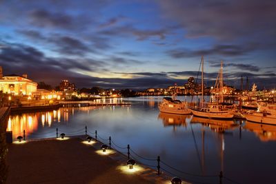 Boats moored at harbor against cloudy sky