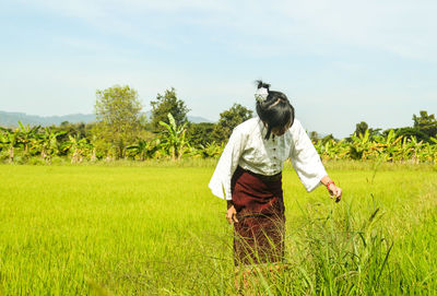 Woman standing on field against sky during sunny day