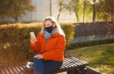 Young woman using phone while sitting on seat