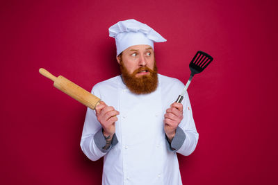Portrait of man holding ice cream against red background