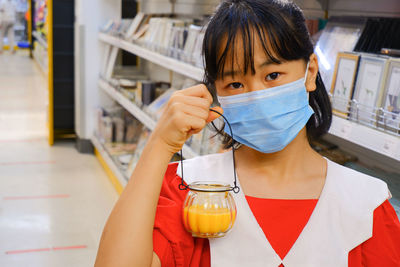 Stage background image of a woman wearing a mask holding a glass bottle in a shop.