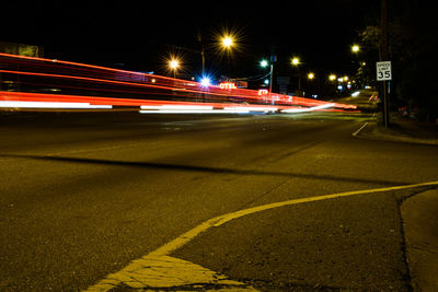 Light trails on road against sky at night