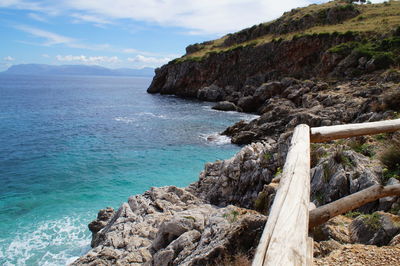 Scenic view of sea by cliff against sky