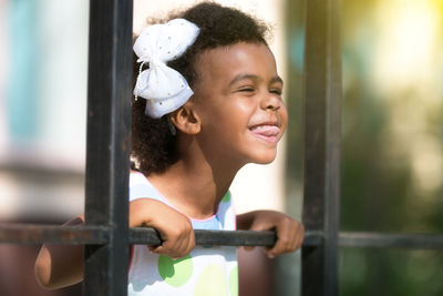 Smiling girl standing by fence outdoors