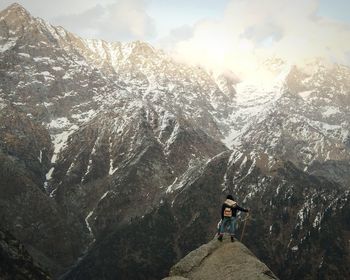 Woman walking on snowcapped mountain against sky