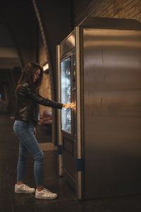 Side view of woman using vending machine