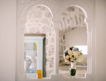 Flower vase against window of building