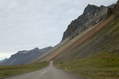 Road by mountains against sky