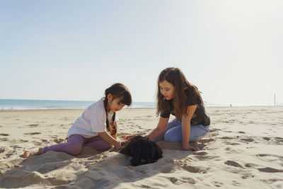 Side view of young woman sitting on beach