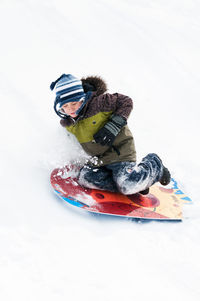 Full length of boy tobogganing on snow