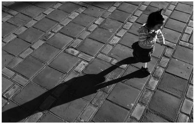 High angle view of boy playing on cobblestone