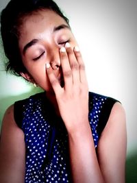 Close-up portrait of young woman against wall
