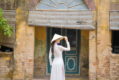 Portrait of woman standing against old building