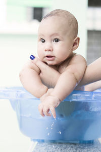 Cropped hands of woman holding baby boy in bathtub