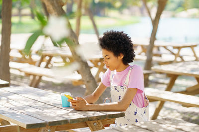 Young woman using mobile phone while sitting at porch