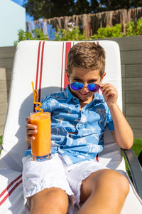 Kid drinking orange juice in the swimming pool