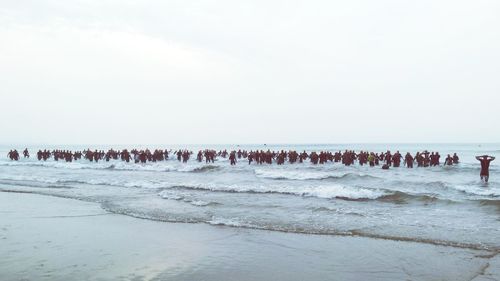 Swimmers at sea during competition against sky