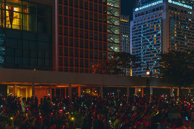 People protesting on street against illuminated buildings at night