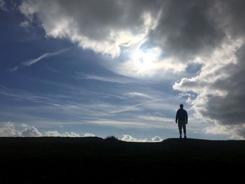 Silhouette man standing on field against sky