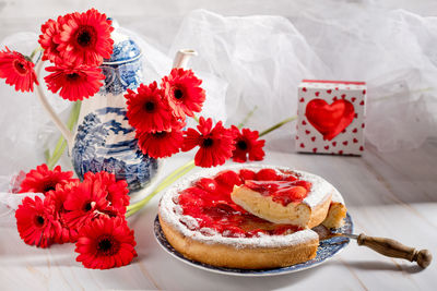 Still life strawberry pie with pudding and a kettle with a bouquet of red gerberas,  valentines gift
