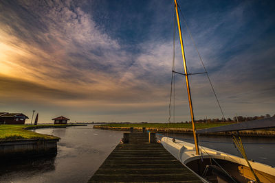 Pier over lake against sky during sunset