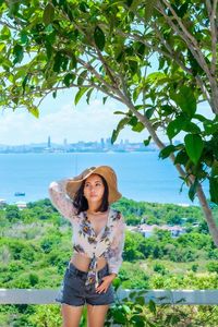 Portrait of beautiful young woman standing against sea