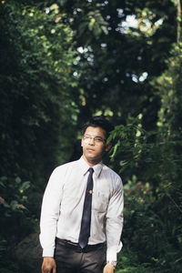 Young man standing by tree