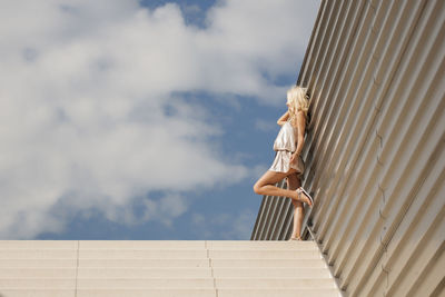 Low angle view of woman standing on steps against sky