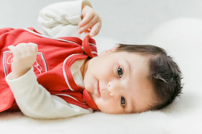 Portrait of cute baby lying on bed at home