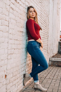 Portrait of young woman leaning against wall