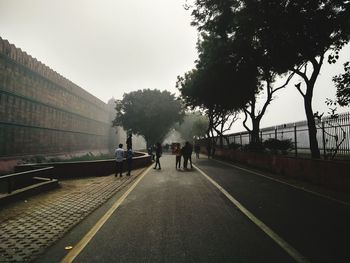 People walking on road in city against clear sky