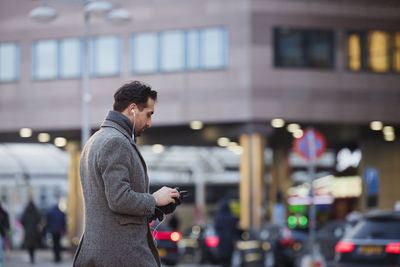 Businessman using phone outdoors in city