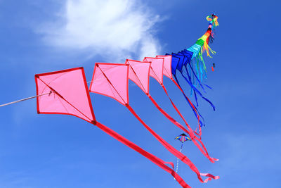 Low angle view of kites flying in blue sky