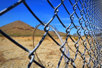 Chainlink fence on field against sky