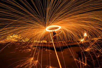 Mid distance view of man spinning wire wool at night