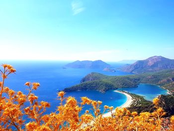 Scenic view of sea and mountains against clear blue sky