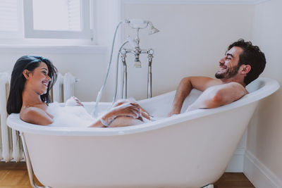Side view of smiling couple sitting in bathtub