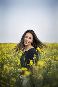 Beautiful young woman with yellow flower in field