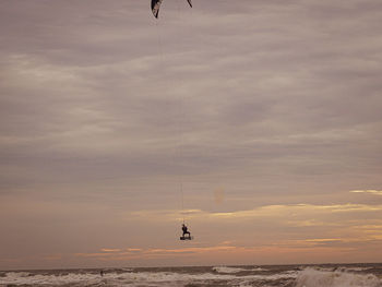 Person parasailing over sea against sky during sunset