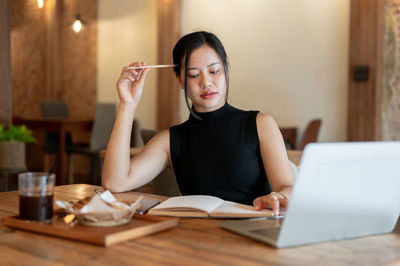 Portrait of young woman using mobile phone while sitting at home