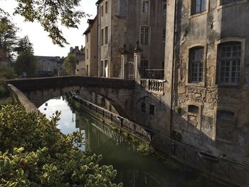 Arch bridge over canal amidst buildings in city