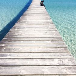 Woman sitting on pier in sea