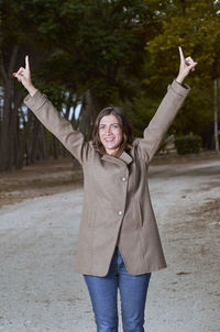 Portrait of young woman with arms outstretched standing outdoors